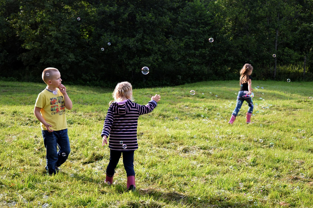 3 kids outside with bubbles